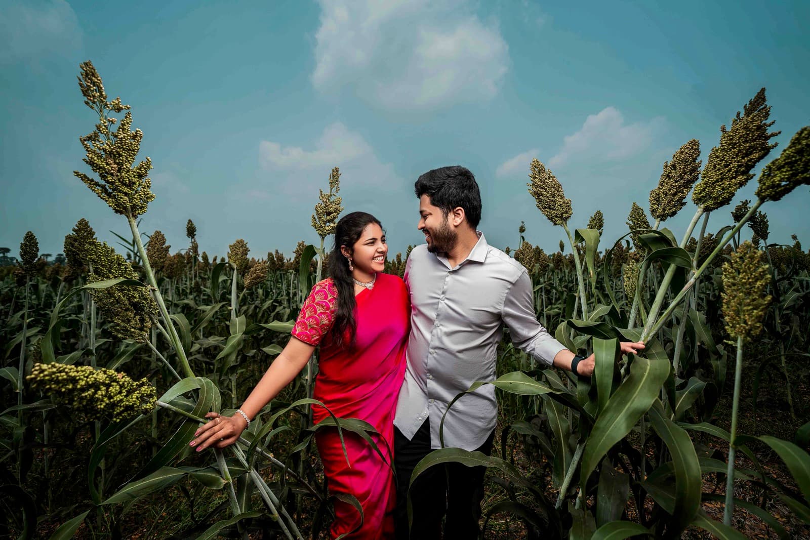 Couple in field with woman in red saree and man in white shirt