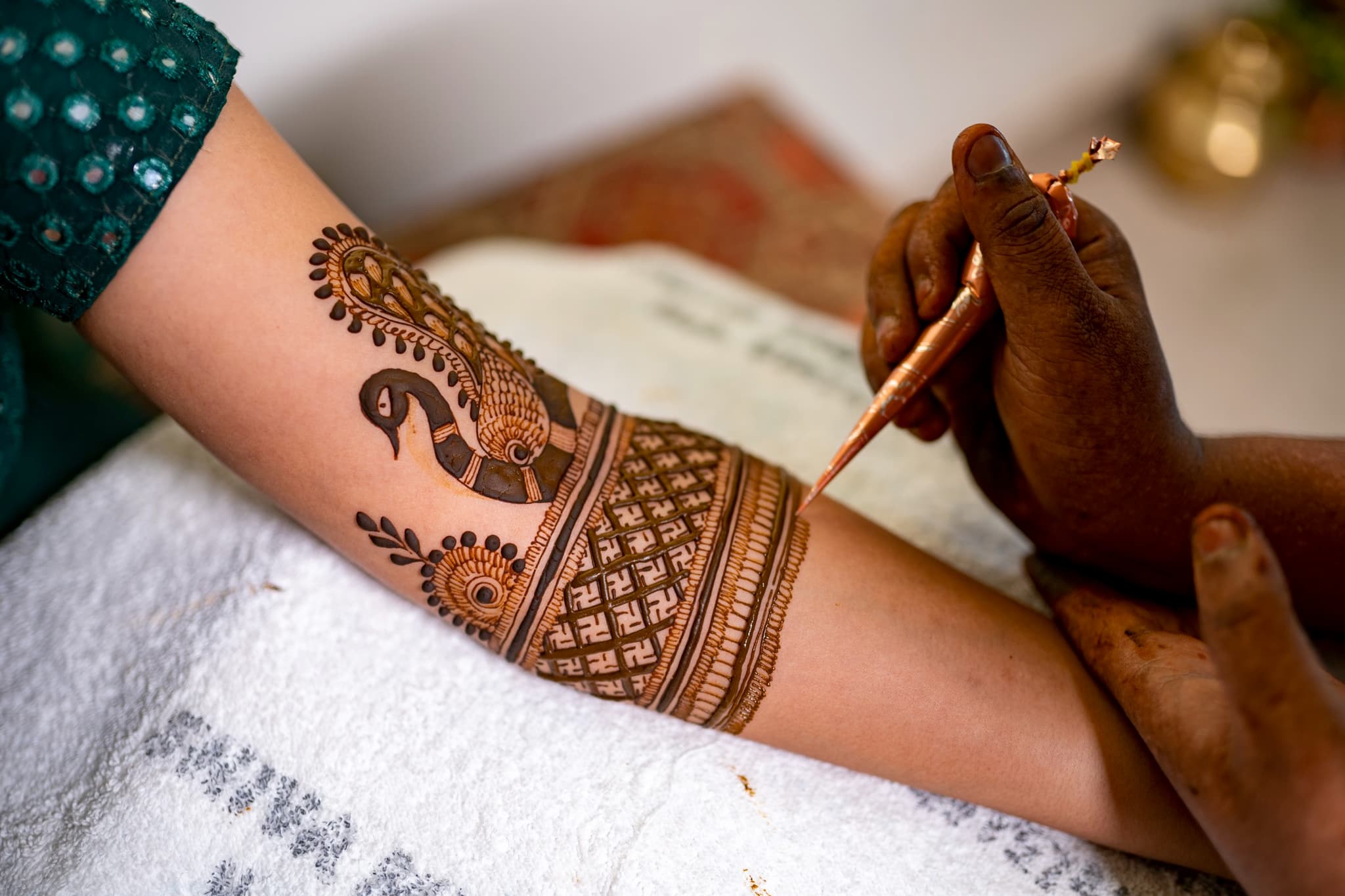 Intricate peacock mehendi design being applied with traditional henna cone