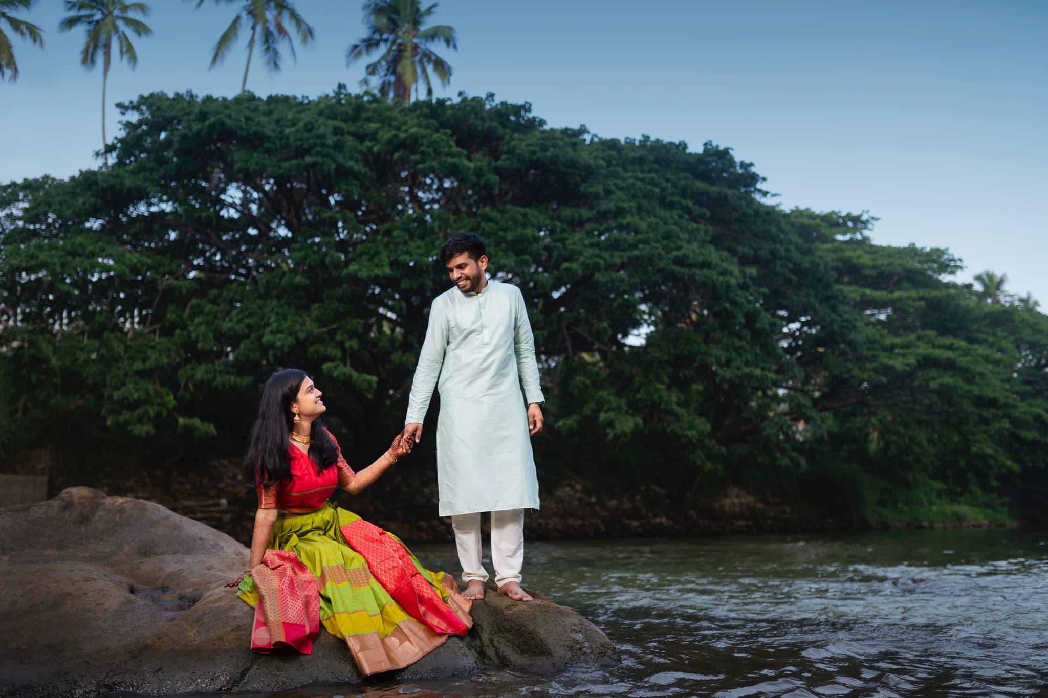 Couple in traditional attire during post-wedding shoot by riverside