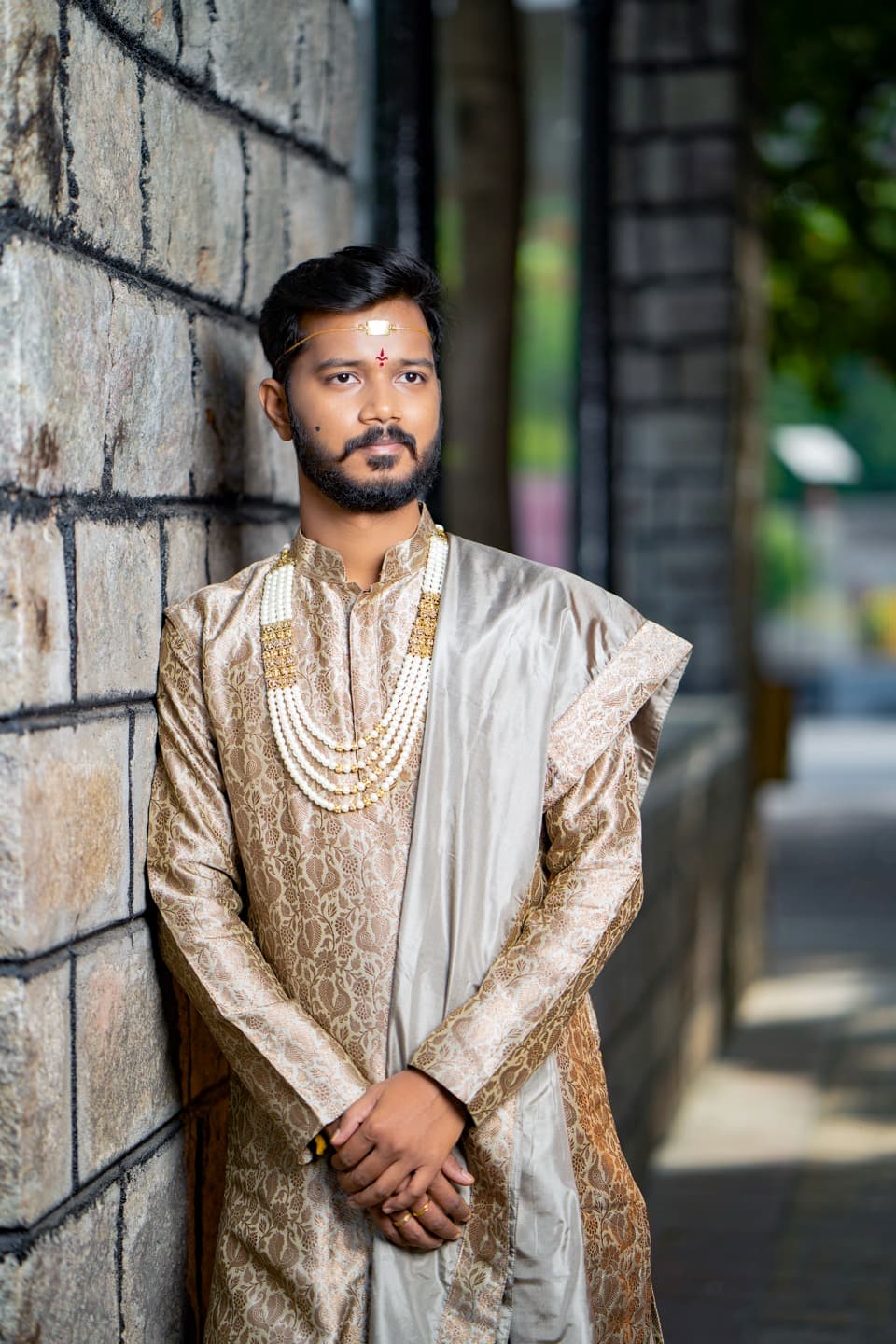 South Indian groom in traditional wedding attire with gold embroidered kurta and pearl necklaces