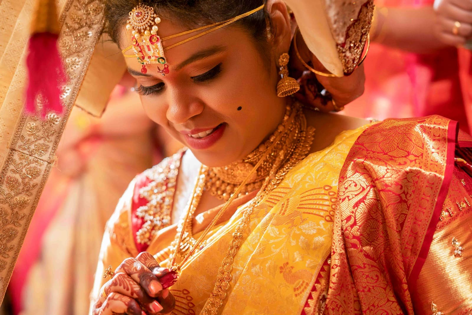 Close-up of South Indian bride in traditional yellow and red saree with gold jewelry