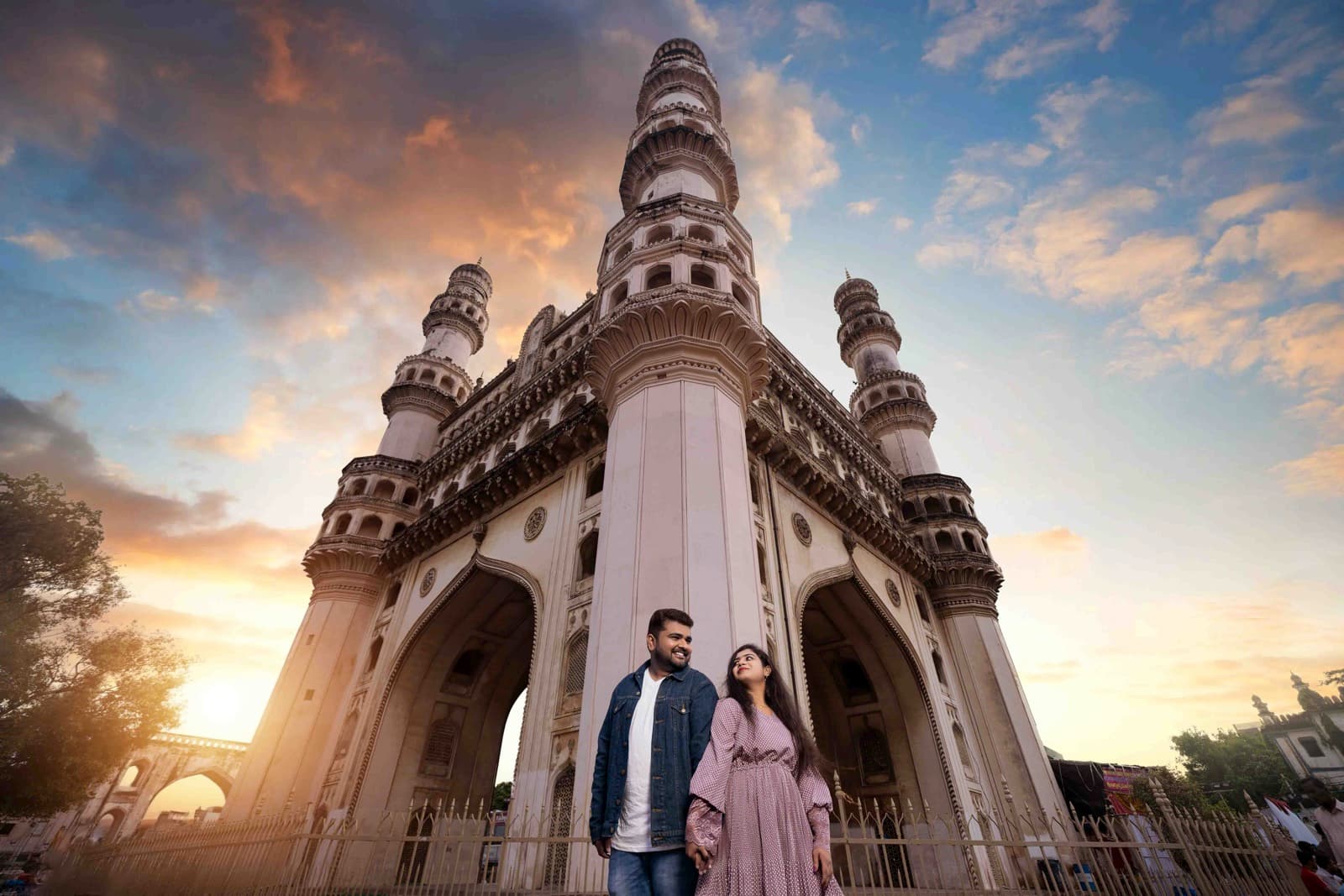 Couple standing in front of Charminar monument at sunset