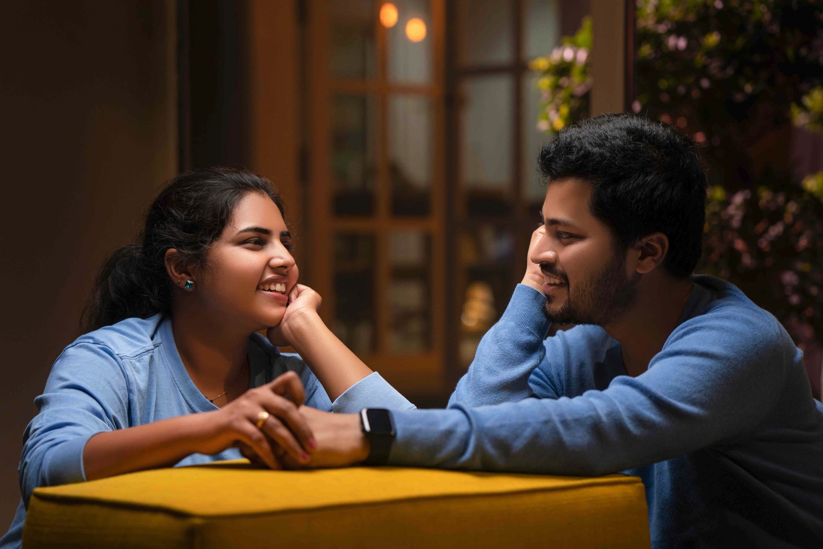 Couple in blue attire sitting at a table looking at each other