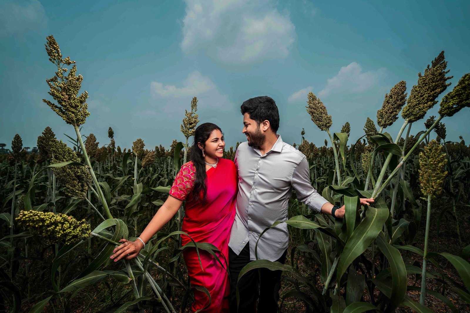Couple in field with woman in red saree and man in white shirt